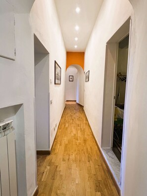 A narrow hallway with wooden flooring, white walls, and a small archway at the end. - Budget Big Apt few steps from Piazza del Campo (Siena)