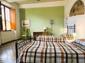 A room with two beds, a desk, a chair, and a picture on the wall. - Budget Big Apt few steps from Piazza del Campo (Siena)