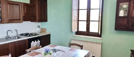 A kitchen with wooden cabinets, a sink, a stove, and a window with curtains.