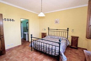 A bedroom with a metal bed frame, a hanging light fixture, and a bathroom visible through an open door. - Apartment in Piazza del Campo area 3 bedrooms 2 bathrooms (Asciano)