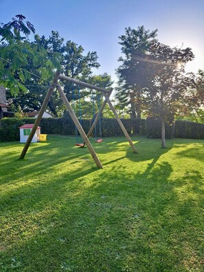 A grassy area with a wooden swing set and a small shed. - Apartment in Piazza del Campo area 3 bedrooms 2 bathrooms (Asciano)