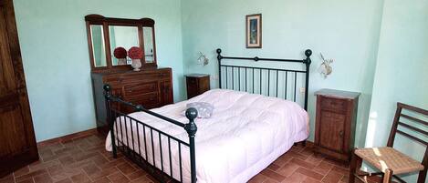 A bedroom with a bed, dresser, chair, and a mirror.