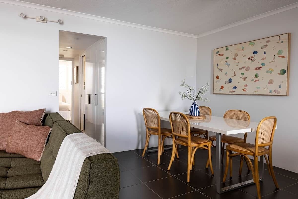 Una sala de estar moderna con un sofá, una mesa de comedor con sillas y una obra de arte colgada en la pared.