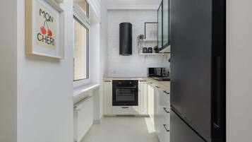 Une cuisine moderne avec des meubles blancs, un réfrigérateur noir et un four encastré.