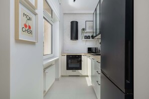 A modern kitchen with white cabinetry, a black refrigerator, and a built-in oven. - Stylish Apartment with Parking | Close to the City Centre (Szczecin)
