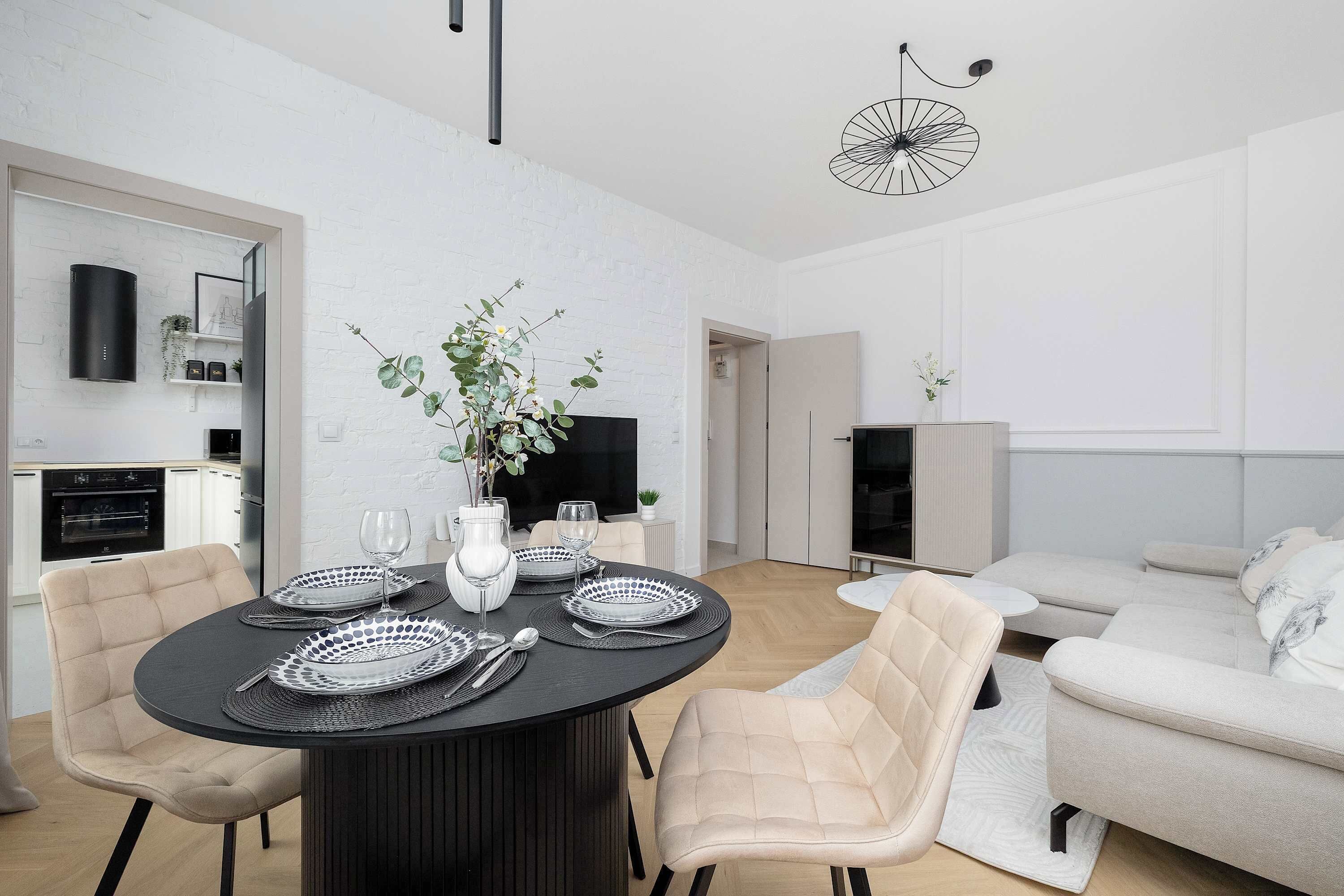 Een moderne woonruimte met een eethoek, bestaande uit een ronde tafel, stoelen en een vaas met bloemen.