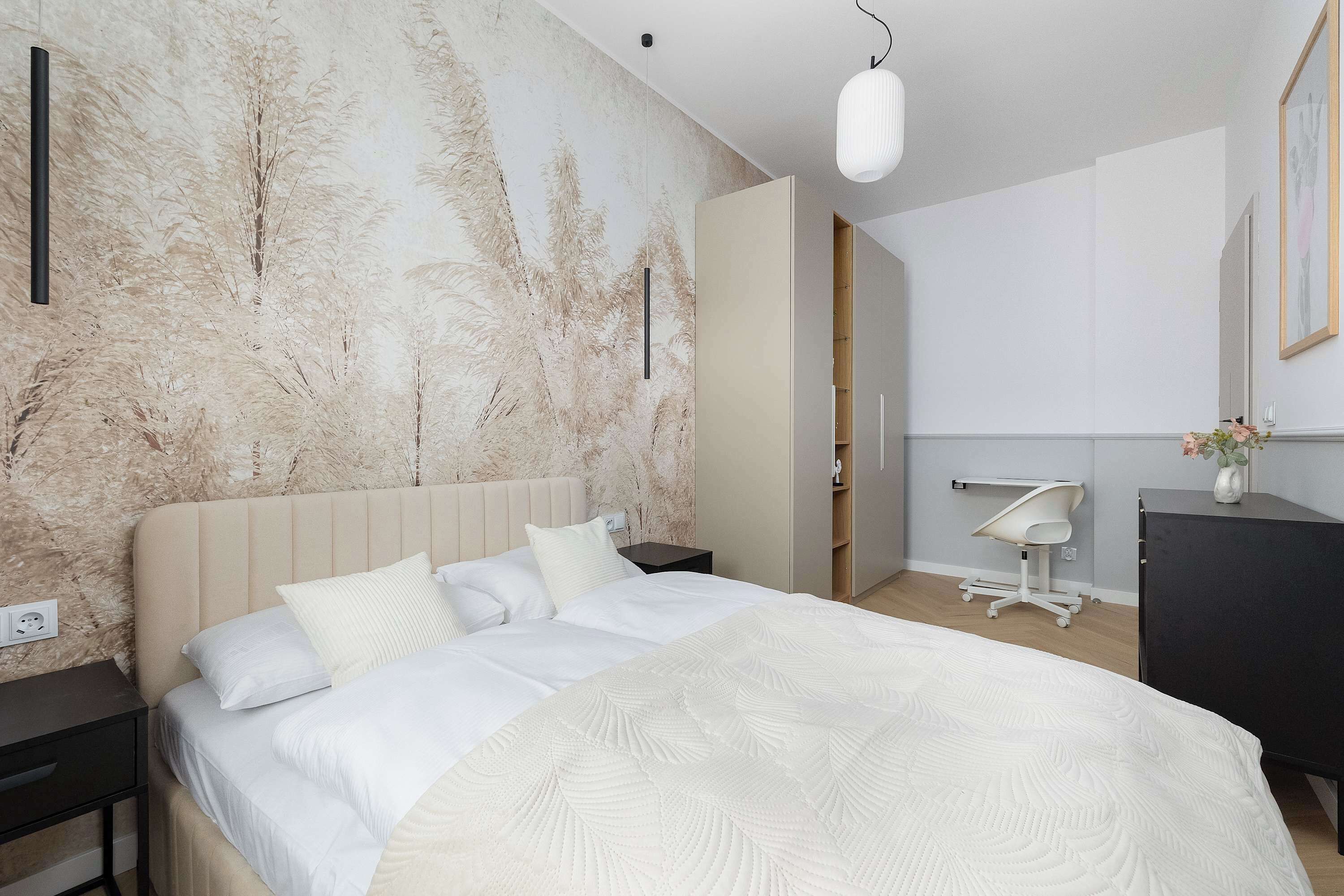 A modern bedroom with a large bed, a nightstand, a dresser, and a desk.