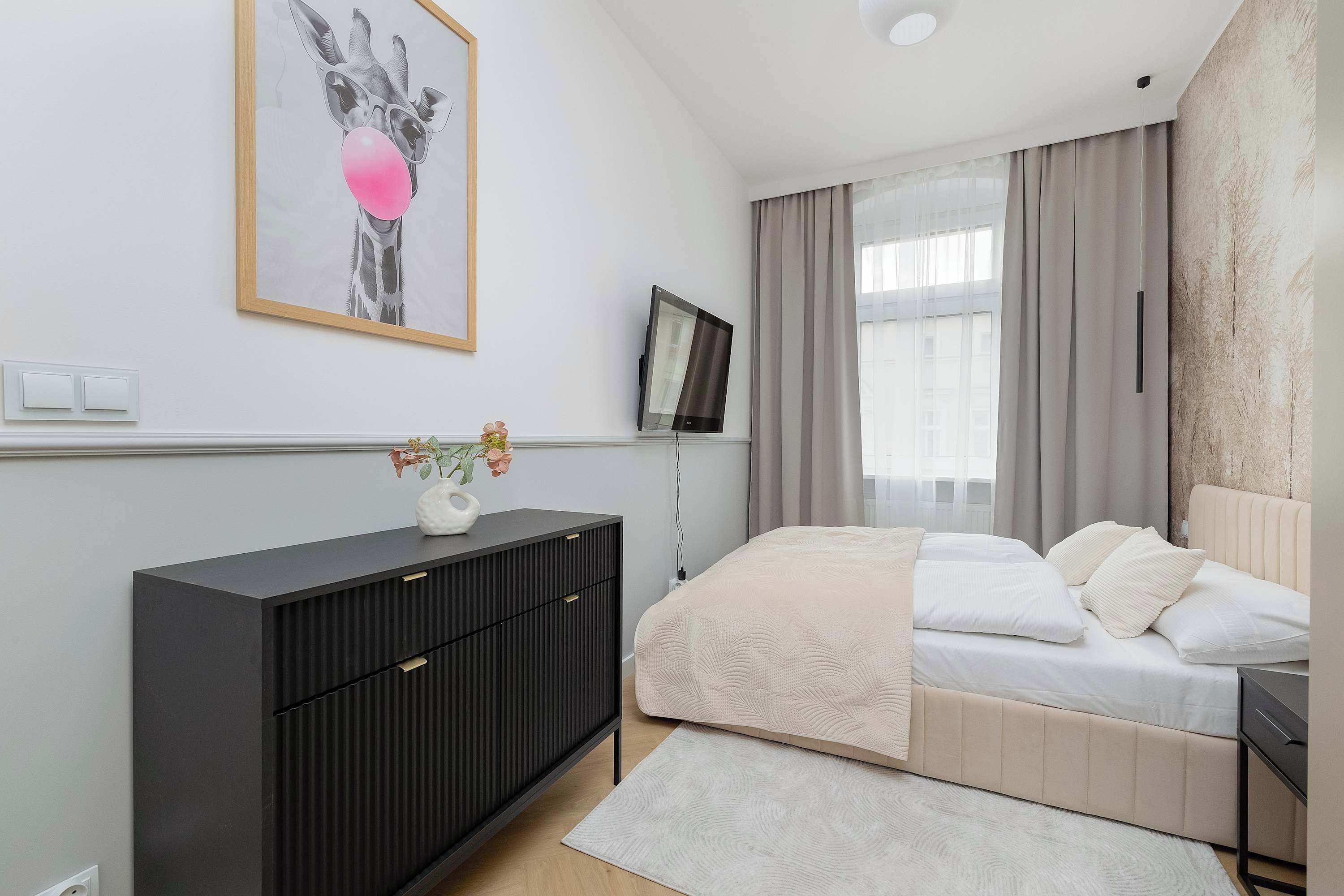 Un dormitorio moderno con cama, cómoda, televisor y un cuadro en la pared.
