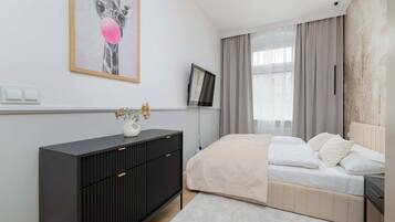 Un dormitorio moderno con cama, cómoda, televisor y un cuadro en la pared.