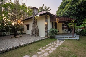 Una casa con fachada de piedra, techo de tejas y porche cubierto.