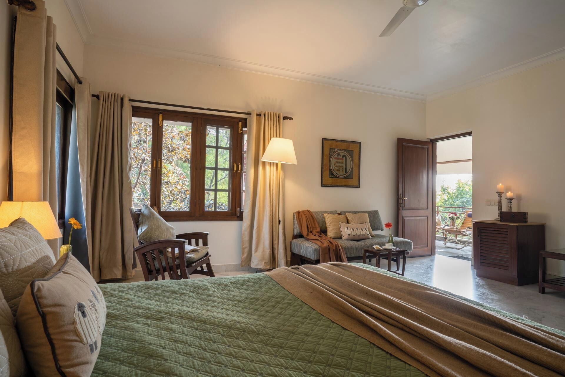Habitación de hotel con cama, sofá, escritorio y ventana con cortinas.