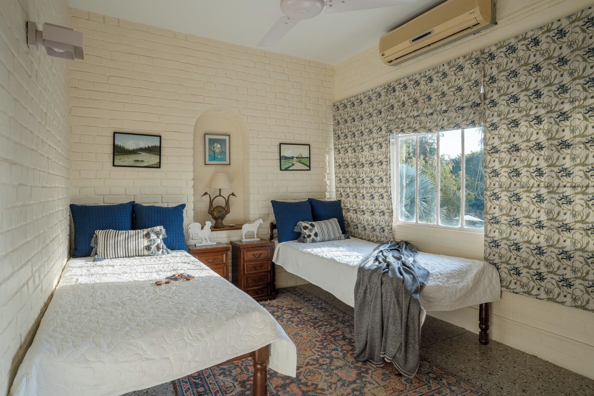 A room with two beds, a patterned wall, and a window with a view.