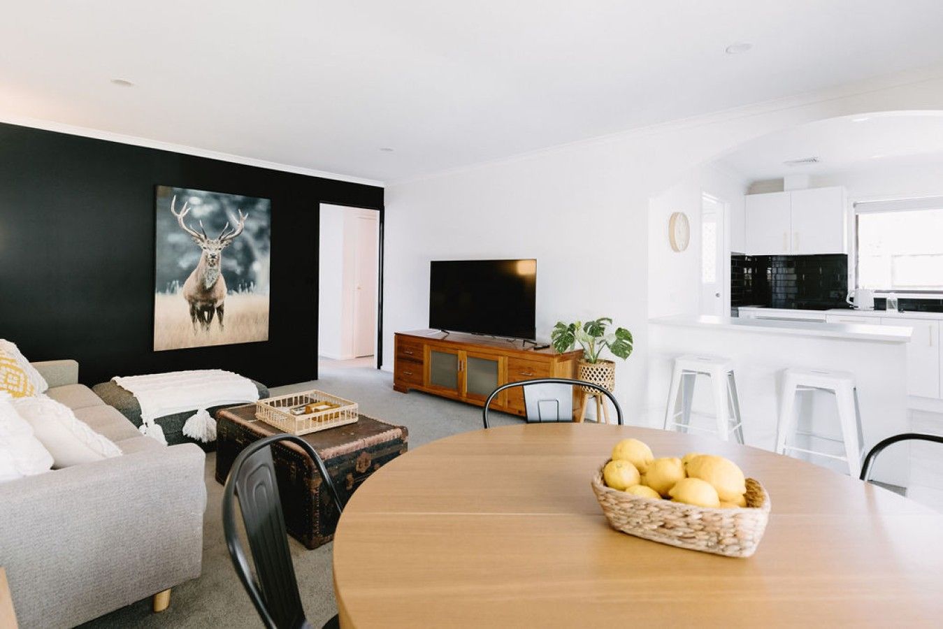 Un salon moderne comprenant un canapé, une table basse, un téléviseur et un coin cuisine avec un four à micro-ondes.