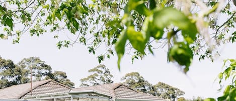 A residential property with a brick house, a covered outdoor seating area, and a well-maintained lawn.