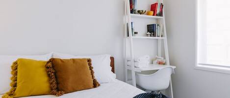 Une chambre à coucher avec un lit, une bibliothèque blanche et une fenêtre.