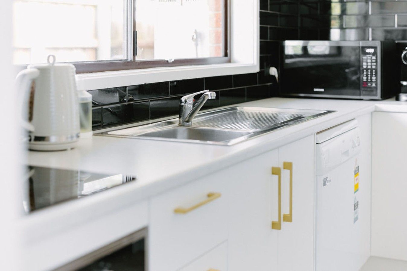 A modern kitchen with a stainless steel sink, a microwave, and a dishwasher.