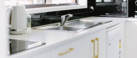 A modern kitchen with a stainless steel sink, a microwave, and a dishwasher.