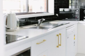 A modern kitchen with a stainless steel sink, a microwave, and a dishwasher. - 2 King Beds | Walk to Town | Sleeps 6 (Sale)