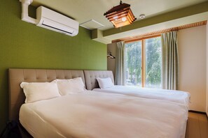 Een tweepersoonsbed met hoofdeinde, een airconditioning, een hanglamp en een raam met gordijnen.