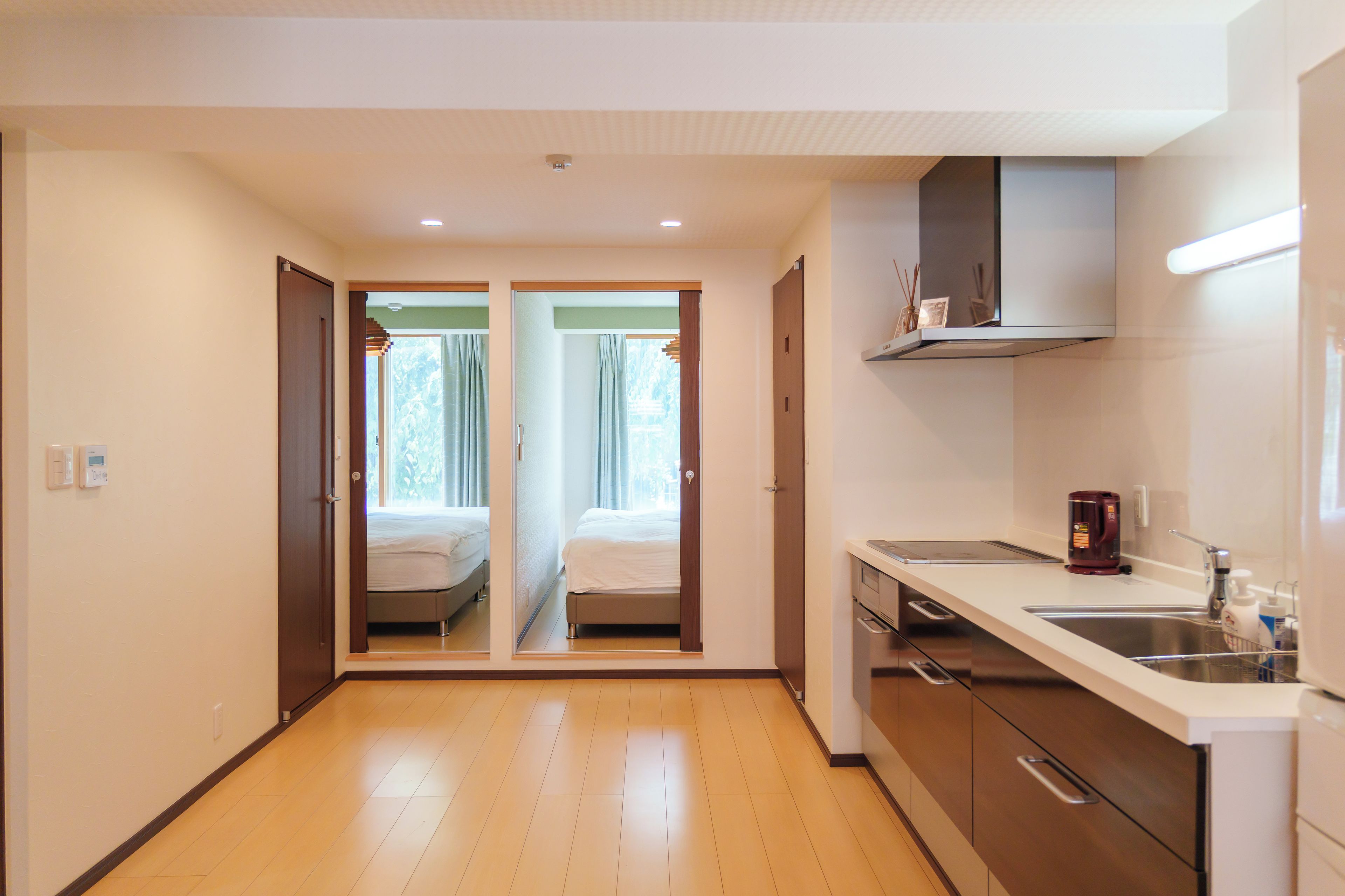 Habitación de hotel con kitchenette, una cama y vistas a través de una puerta.