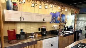 A kitchen with bamboo paneling, a coffee maker, and a sink.