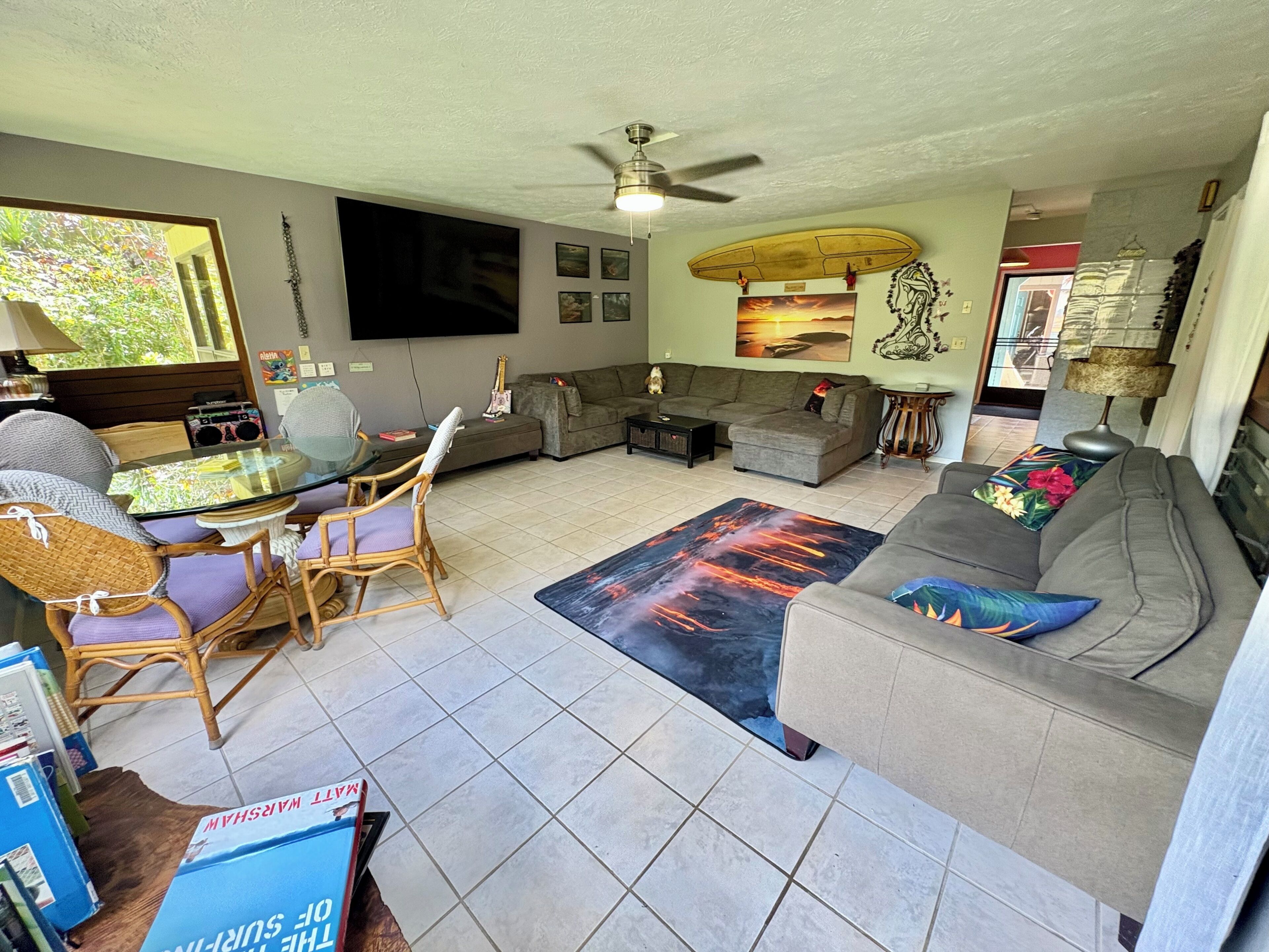 A living room with a flat-screen TV, two sofas, a coffee table, and a dining area with chairs and a glass table.