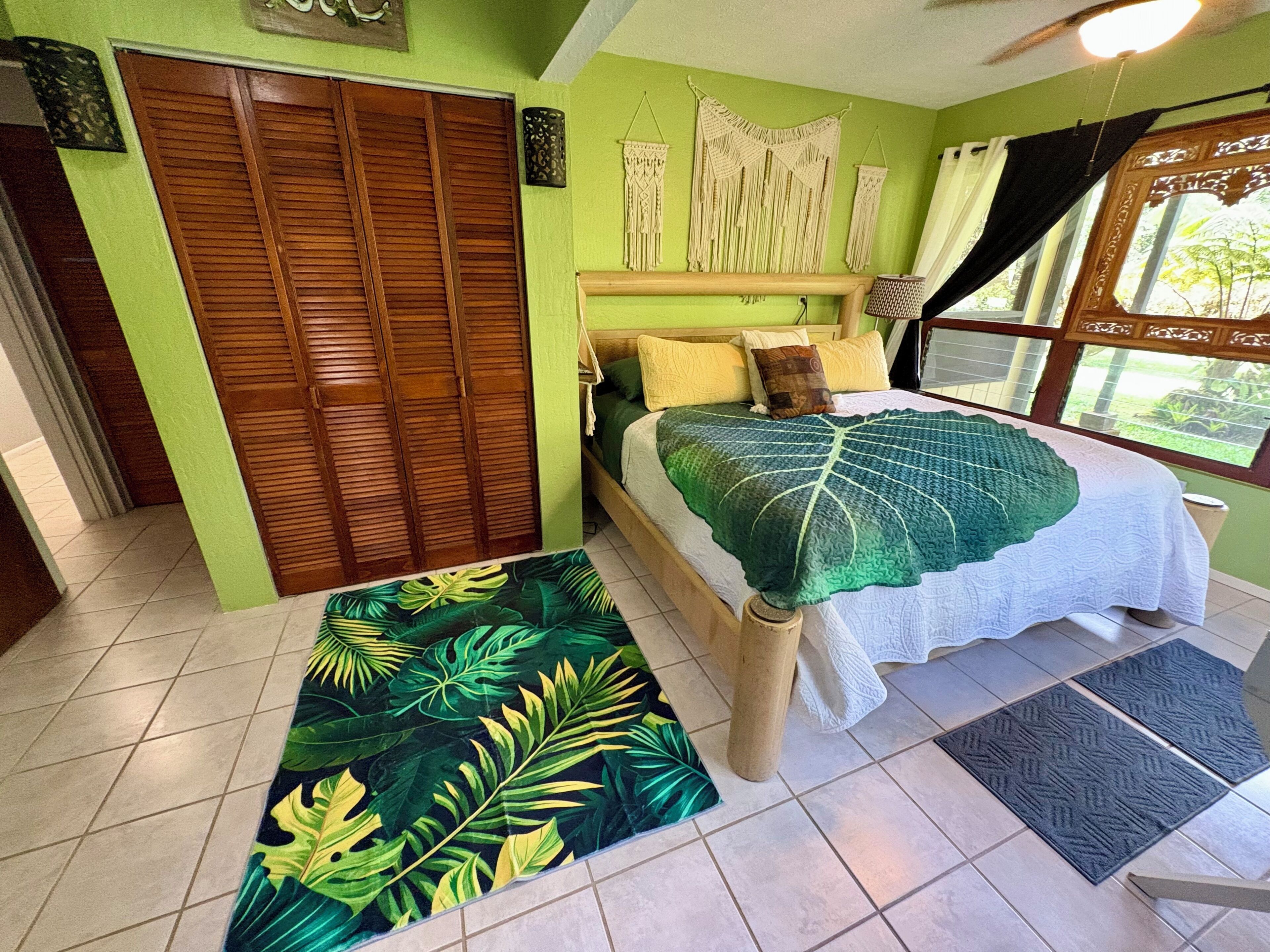 A bedroom with a bed, a wooden wardrobe, a green wall, and a window with curtains.