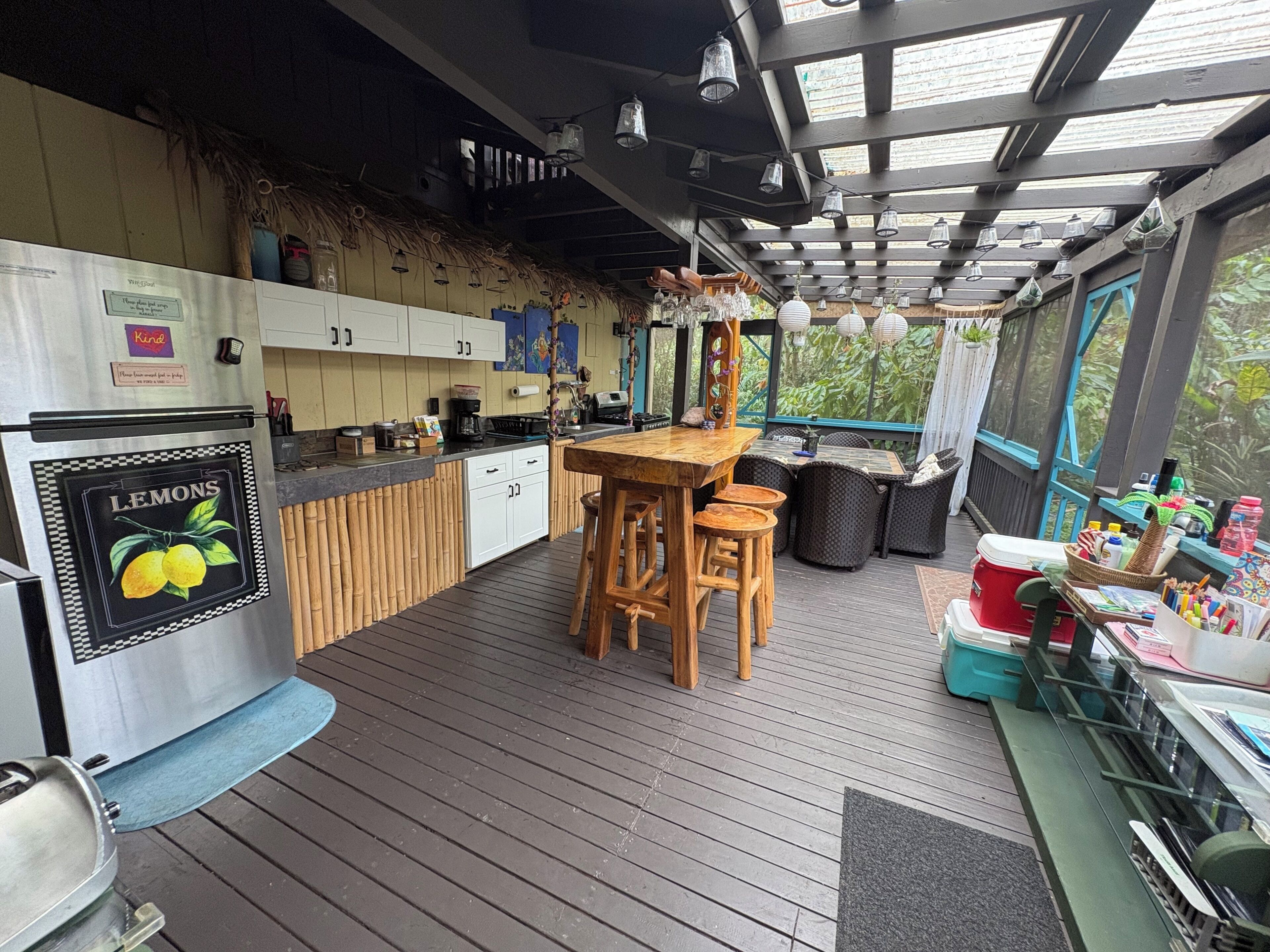 A kitchen with a wooden island, a refrigerator, and a dining area with chairs.