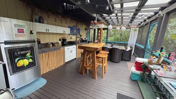 A kitchen with a wooden island, a refrigerator, and a dining area with chairs.
