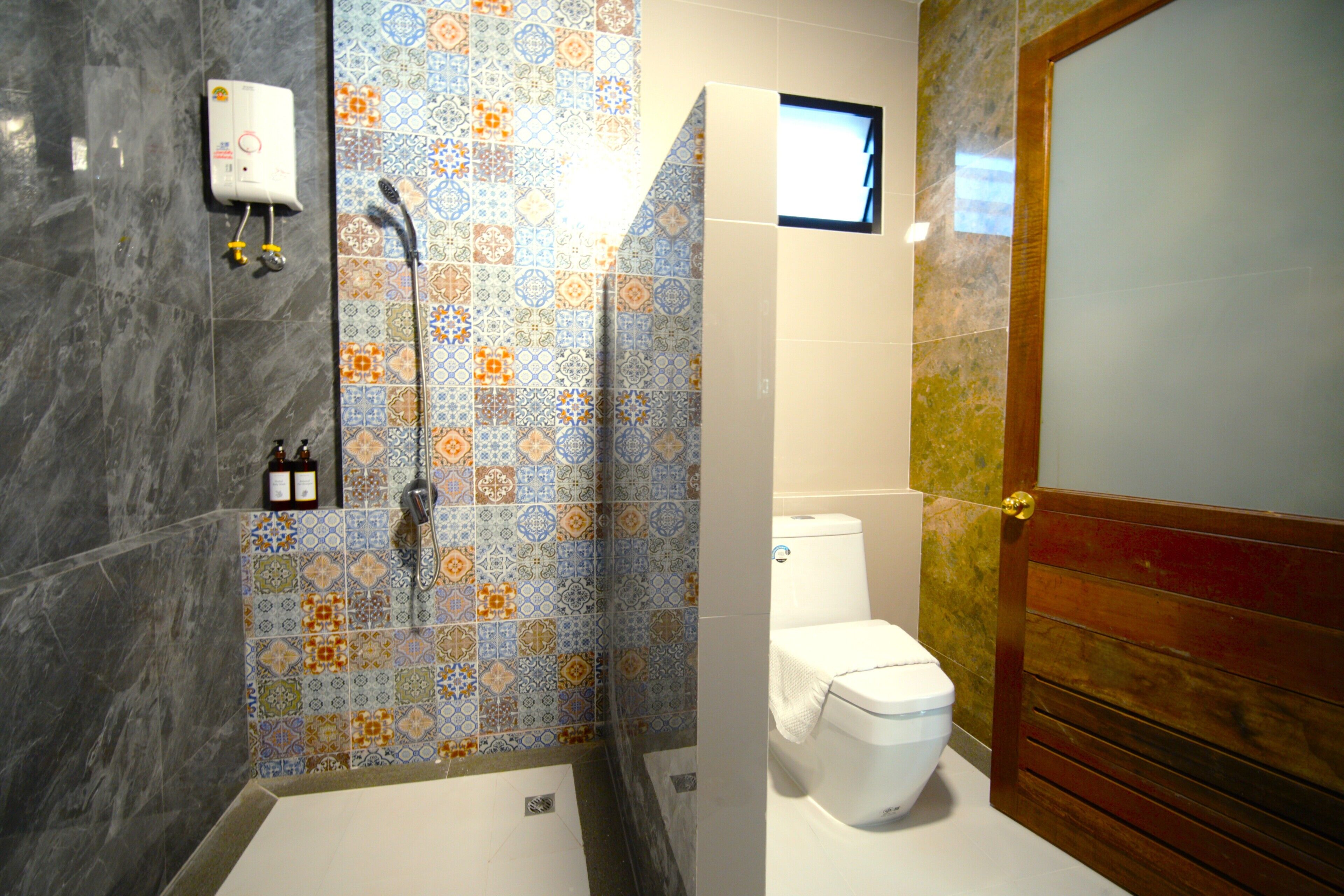 A bathroom with a shower, toilet, and a tiled wall with a geometric pattern.