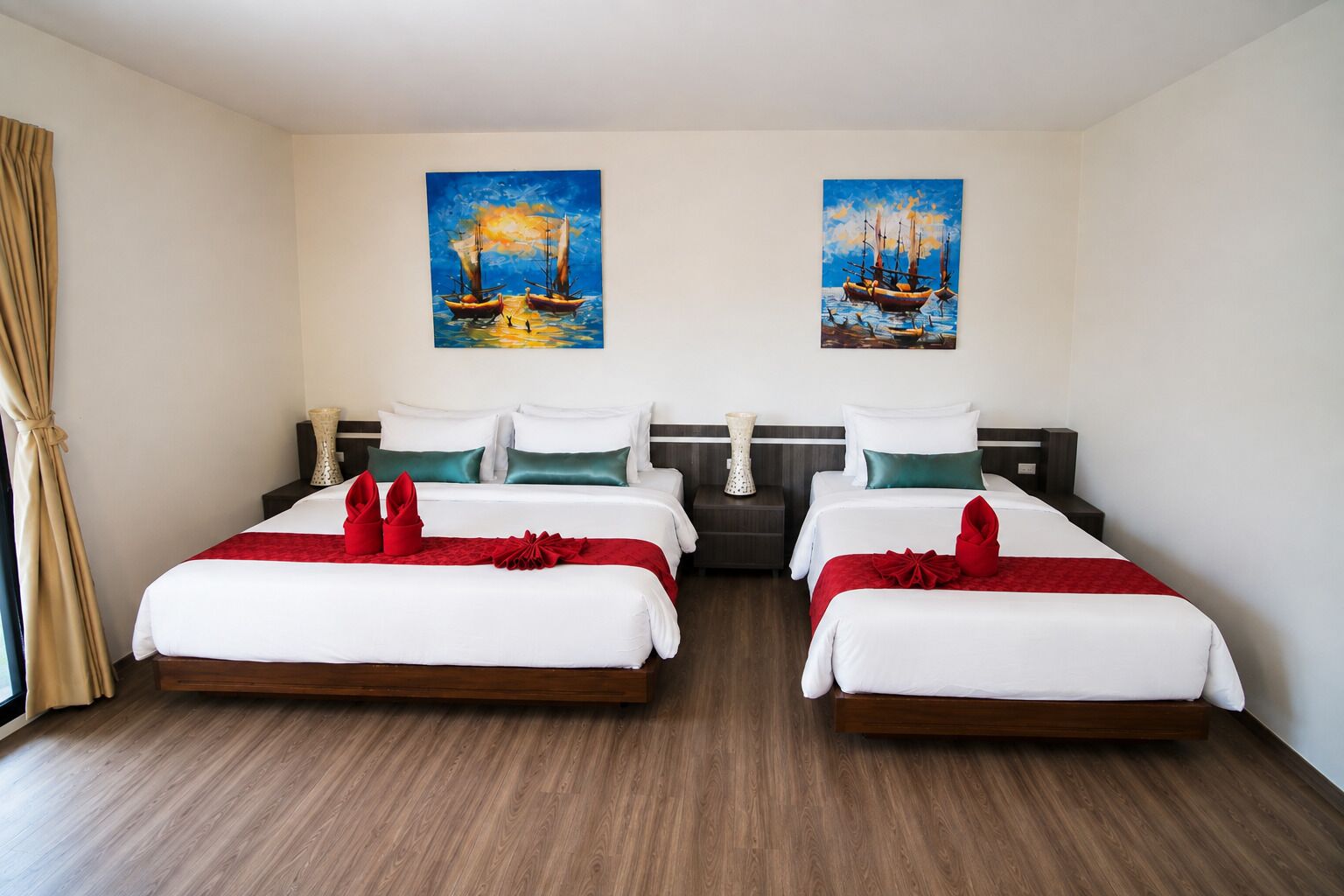 Quarto de hotel com duas camas, piso de madeira e duas pinturas na parede.
