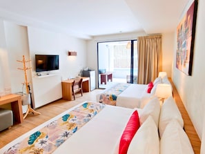 Hotellihuone, jossa on kaksi sänkyä, työpöytä, televisio ja parveke, jossa on verhot.