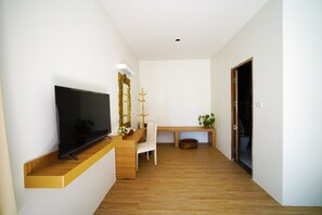 Et moderne hotelværelse med et fladskærms-tv, et træskab, en hvid stol, en bænk og en dør, der fører til et andet værelse.