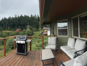 A deck with a barbecue grill, outdoor seating, and a view of forested hills. - Serenity Pointe at Foster Lake - 3BR  2B Lakeview (Sweet Home)