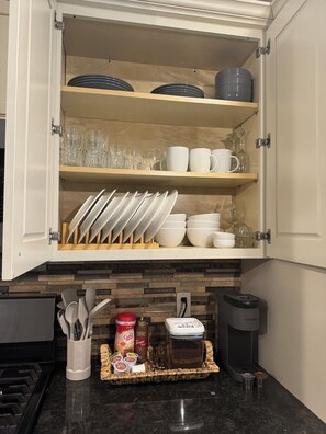A kitchen with a cabinet containing plates, glasses, and bowls. There is a coffee maker and a toaster on the counter. - Serenity Pointe at Foster Lake - 3BR  2B Lakeview (Sweet Home)