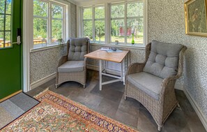 A corner room with wicker chairs, a small table, and a view of the outdoors through large windows. - 2 bedroom lovely home in Fagerhult (Fagerhult)