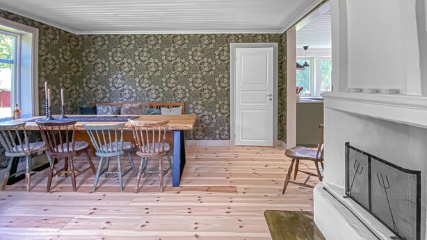 Ein Essbereich mit Holztisch und -stühlen, einem Kamin und einer Tür zu einem anderen Raum.