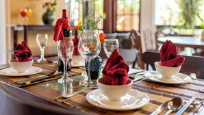 A dining table set with white plates, red napkins, and clear glassware. - Cedar Boutique Hoi An (Da Nang)