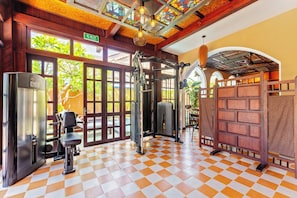 Una palestra con attrezzature per esercizi, pavimento a scacchi e vista sull'esterno.