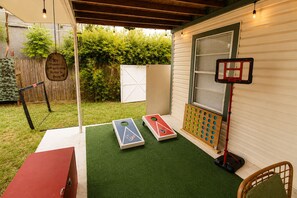 A backyard with a green artificial turf, a wooden fence, a basketball hoop, and a wooden sign. - Modern 3BR Houston Home Near Downtown w/ Patio (Houston)