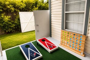 Ein Garten mit zwei Shuffleboard-Platten, einer Holzwand mit Haken und einer weißen Garagentür.