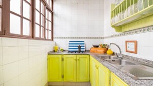 A kitchen with yellow cabinets, a sink, and a window with blinds.