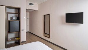Une chambre d’hôtel avec un lit, une armoire, une télévision et un miroir.