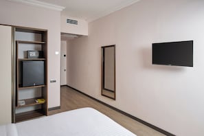 Una habitación de hotel con una cama, un armario, un televisor y un espejo.
