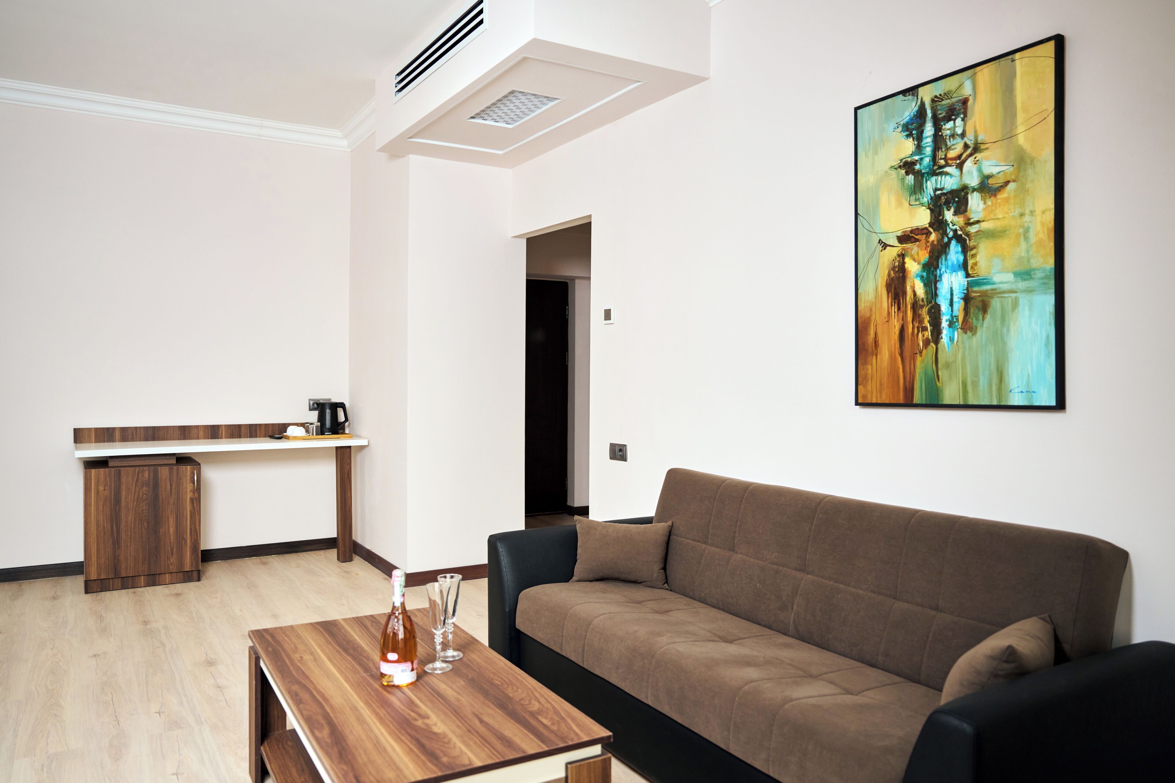 Uma sala de estar moderna com uma mesa de centro de madeira, um sofá marrom e um quadro na parede.
