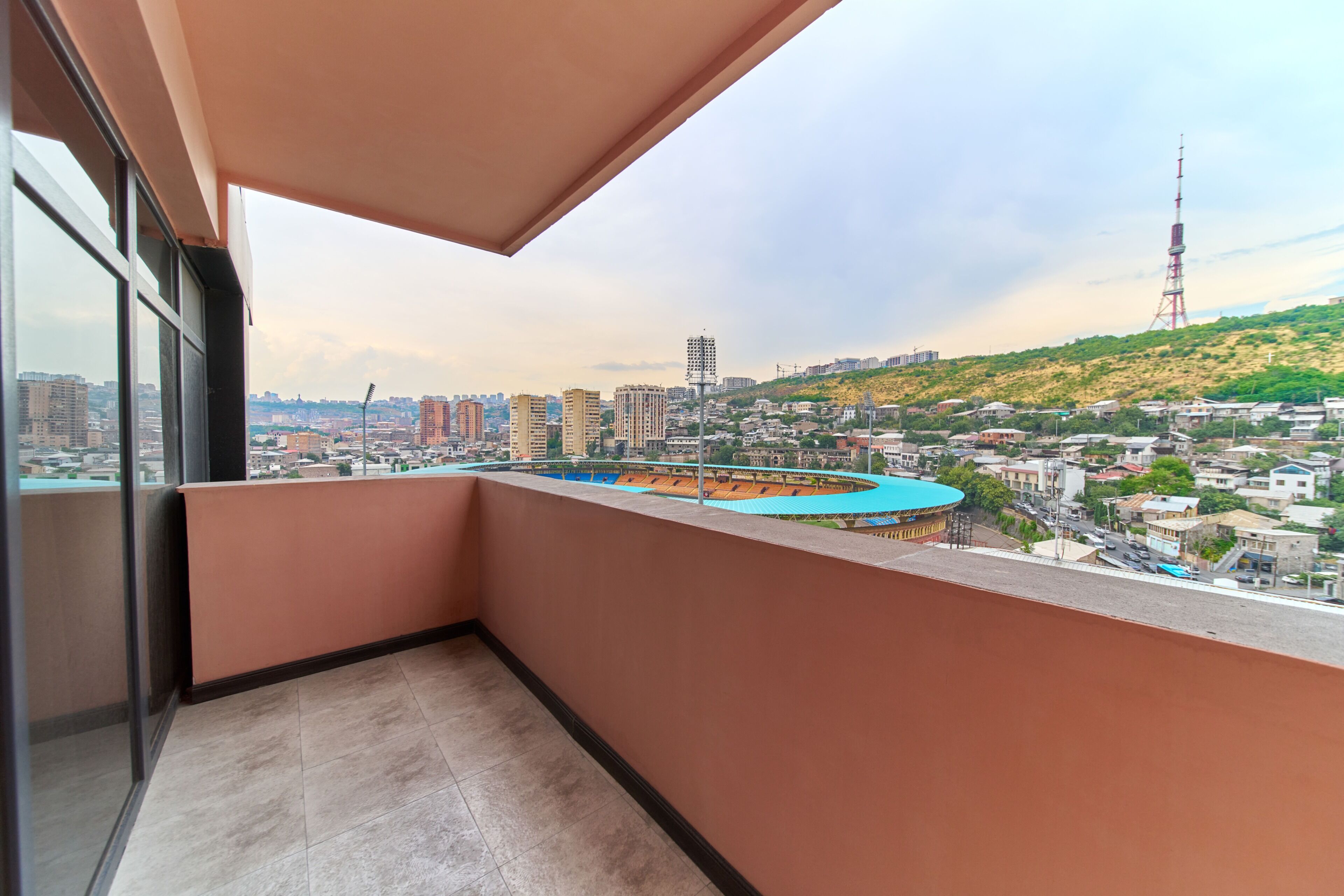 A balcony with a view of a cityscape, including buildings and a hill.
