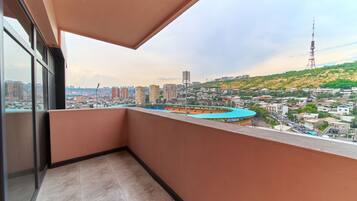 A balcony with a view of a cityscape, including buildings and a hill.
