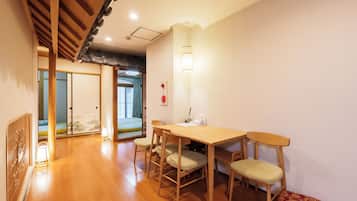 A traditional Japanese room with tatami flooring, a low table with chairs, a shoji screen door, and a sliding door leading to a balcony.