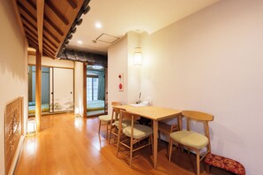 A traditional Japanese room with tatami flooring, a low table with chairs, a shoji screen door, and a sliding door leading to a balcony. - SERENE | Dotonbori, 2nd Floor | 85 ㎡, 3 bedrooms, 2 bathrooms | Private, Entire Floor (Osaka)