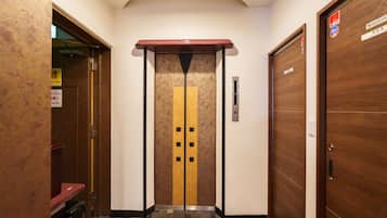 An elevator with a yellow stripe and black squares, flanked by wooden doors with a sign above.